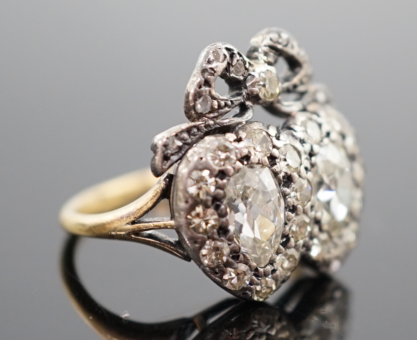 A 19th century gold, silver and diamond cluster set twin hearts ring, with ribbon bow surmounted